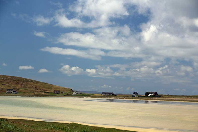 Northon village at low tide with the bay of white sand under a blue sky with white clouds