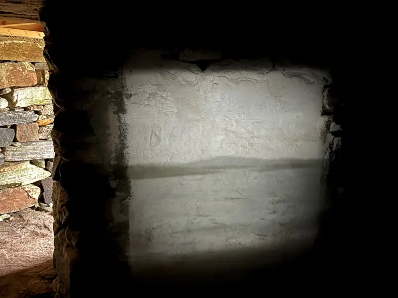 Inside hut of the shadows the grey scenery from outside is reflected on the wall